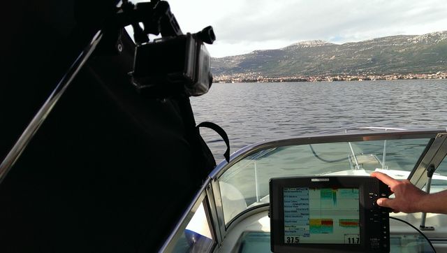 Chartplotter on a boat's console, next to the wheel